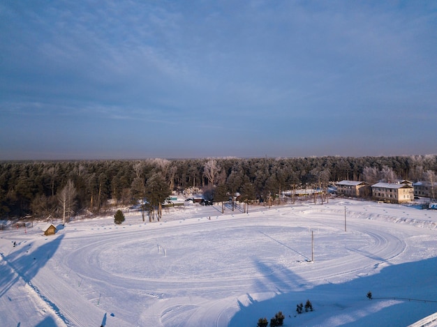 Fotografía aérea de un bosque verde y un estadio con una casa de carretera en un frío día de invierno