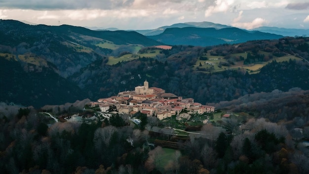 Fotografia aérea de uma pequena aldeia na colina cercada por montanhas arborizadas