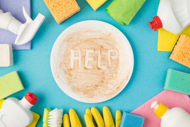 Fotografía aérea del equipo para la limpieza y el plato sucio con ayuda de inscripción en el medio aislado en el fondo azul