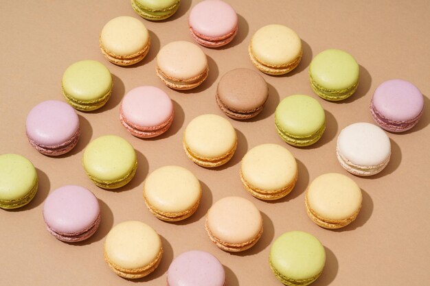 Foto una fotografía aérea de una superficie de mesa beige con una variedad de macarrones coloridos en filas ordenadas