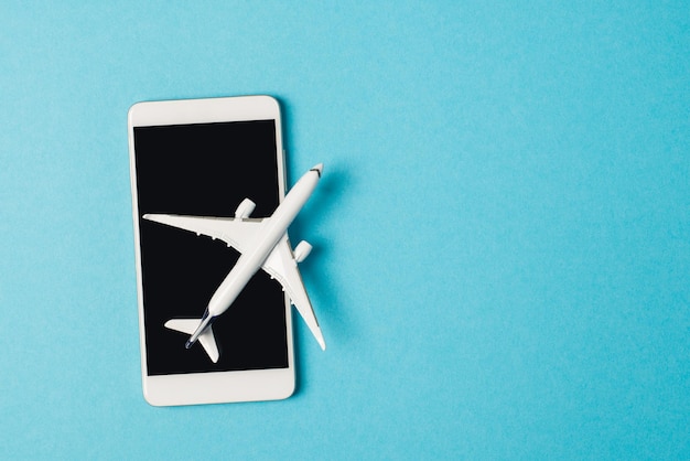 Fotografía aérea de un teléfono inteligente y un avión aislado en el fondo azul con espacio de copia