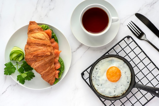 Fotografía de alimentos de desayuno, croissant, huevo frito, té, sándwich de salmón