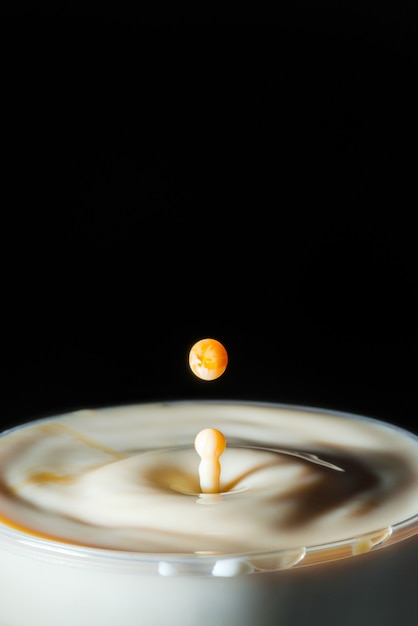 Fotografía de alta velocidad de una gota de leche de caramelo sobre fondo negro en el estudio