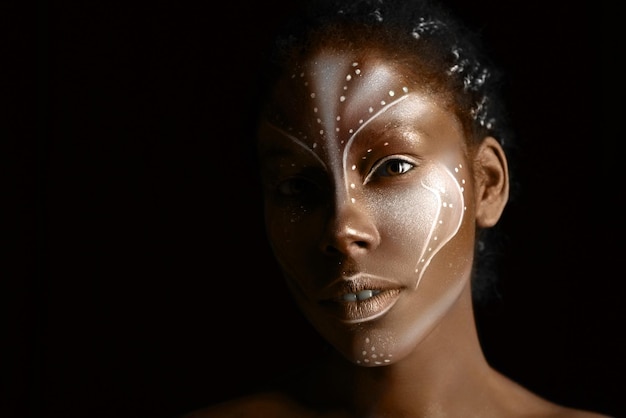 Fotografía artística de una mujer africana con pinturas étnicas tribales en su rostro