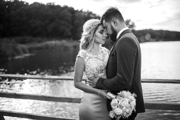 Fotografía en blanco y negro elegante pareja de recién casados posando en un puente el día de la boda