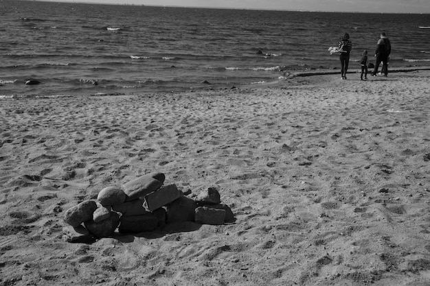 Fotografía en blanco y negro de gente caminando por la playa con el fondo del mar