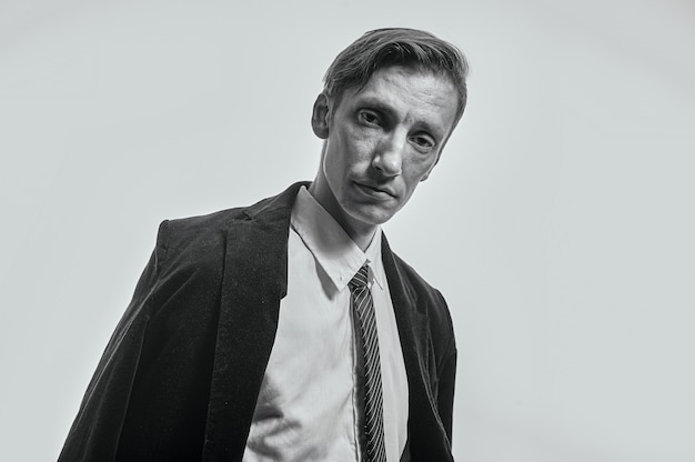 Fotografía en blanco y negro Un hombre con ropa de oficina sobre un fondo gris nos mira con cansancio