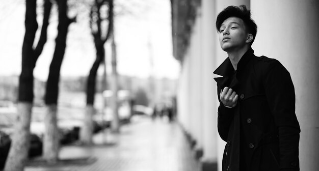 Fotografía en blanco y negro de un joven asiático al aire libre posando en la cámara