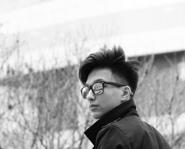 Fotografía en blanco y negro de un joven asiático al aire libre posando en la cámara