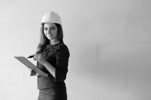 Fotografía en blanco y negro de una mujer arquitecta en el sitio de construcción con dibujos y cuaderno