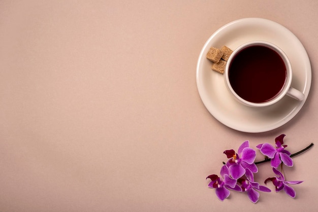 Fotografía en blanco de taza de té y orquídea.