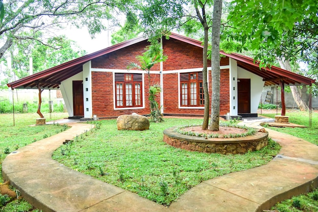 Una fotografía de una casa de estilo en el jardín con hierba verde y árbol