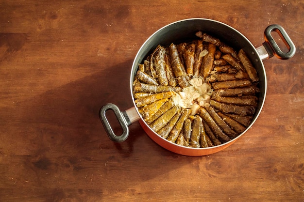 Fotografía cenital de una comida árabe tradicional de hojas de parra con carne de pollo servida con limones