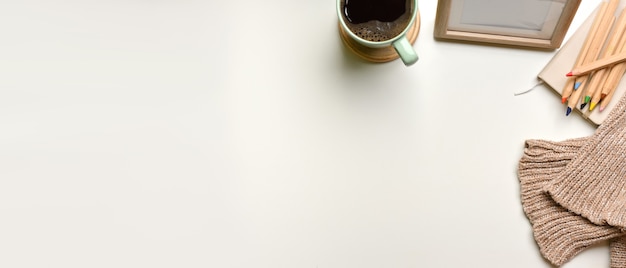 Fotografía cenital del espacio de trabajo simple con marco de taza, lápices de colores, suéter y espacio de copia