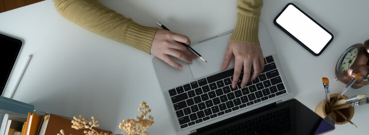Foto fotografía cenital de una estudiante universitaria haciendo una tarea con computadora portátil y teléfono inteligente
