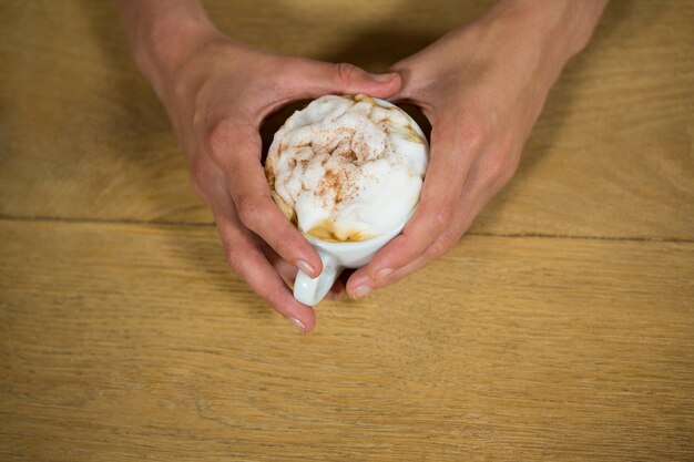 Foto fotografía cenital de las manos del hombre sosteniendo la taza de café en la mesa de la cafetería