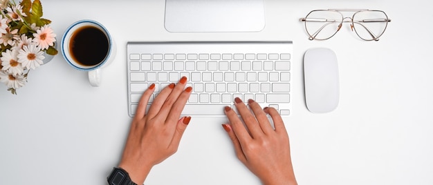 Fotografía cenital de mujer elegante que trabaja con la computadora en el escritorio blanco.