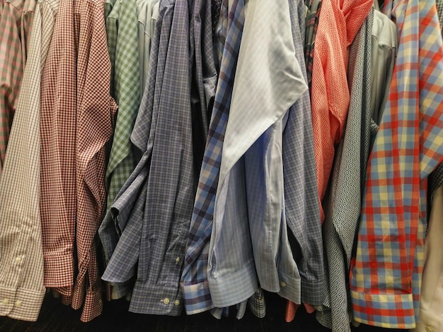 Foto fotografía completa de camisas de varios colores colgando en el estante