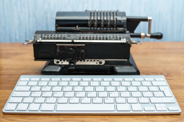 Foto fotografia conceitual, uma velha calculadora enferrujada no fundo e um teclado de computador branco moderno na frente