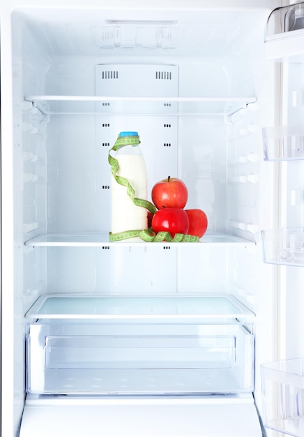 Fotografía conceptual de la dieta de manzana y botella de leche con tipo de medición en el estante del refrigerador