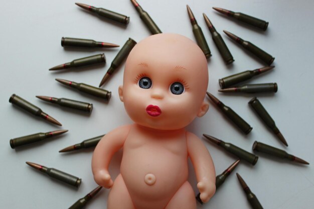 Fotografía conceptual de la infancia perdida Cara ingenua de una muñeca infantil tendida sobre una bala vista superior