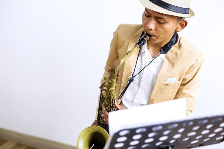 Foto fotografía cortada de un joven asiático tocando jazz con saxofón mientras está sentado