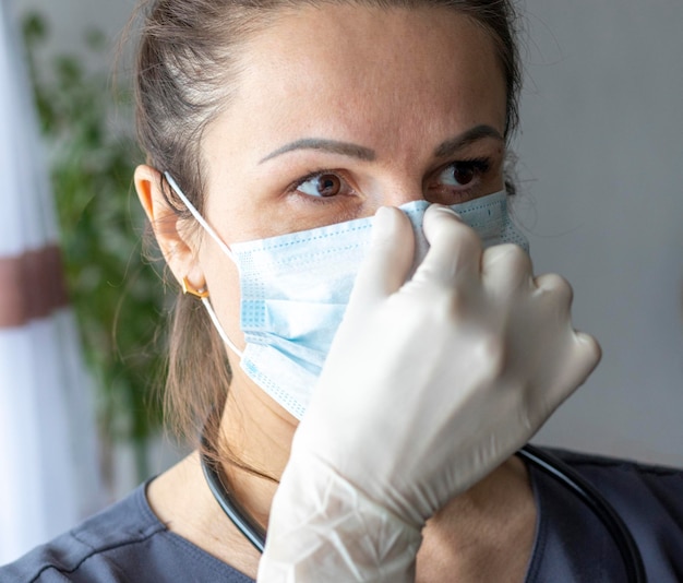 Fotografia da enfermeira com luvas médicas segurando máscara médica Saúde