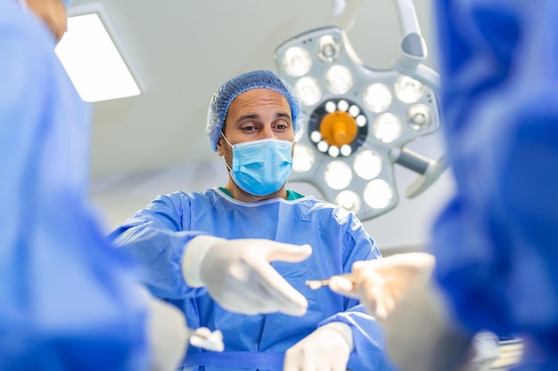 Fotografia de baixo ângulo na sala de cirurgia Assistente entrega instrumentos aos cirurgiões durante a operação Cirurgiões realizam a operação Médicos profissionais realizam a cirurgia