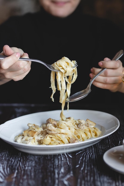 Foto fotografia de comida massa italiana mãos de menina com garfo e colher closeup