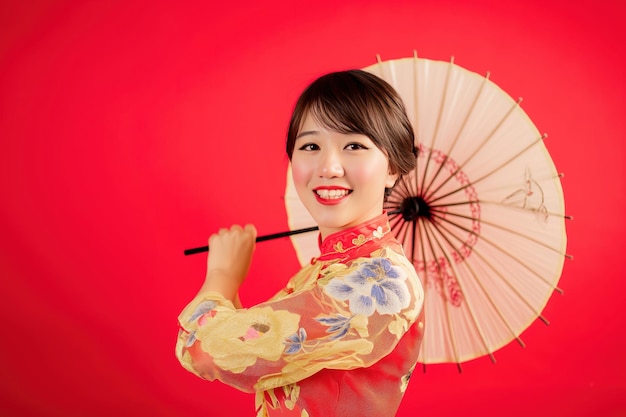 Fotografia de retrato de mulher chinesa asiática sorrindo em vestido tradicional cheongsam qipao em fundo vermelho conceito de festival de ano novo chinês