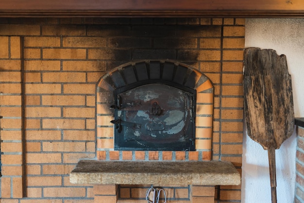 Fotografia de um forno de pizza tradicional de tijolos com uma velha casca de madeira em luz brilhante