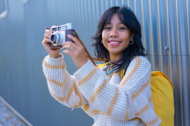 Fotografia de uma jovem asiática com um conceito de férias de câmera fotográfica vintage com uma mochila amarela