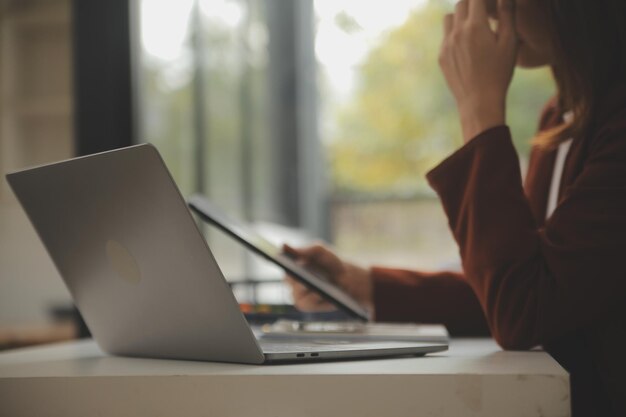 Fotografia de uma jovem empresária asiática trabalhando em um laptop em sua estação de trabalho