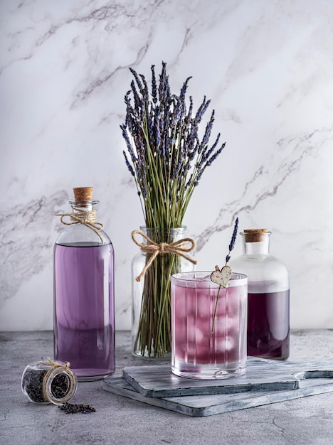 Fotografia de vidro de garrafas de buquê de bebida de lavanda em um fundo de mármore