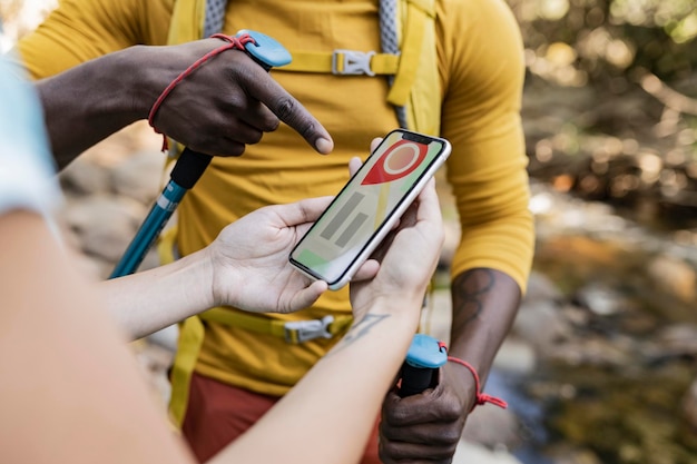 Fotografia detalhada de um casal com um telefone celular na mão fazendo trekking vendo o mapa de satélite encontrando o caminho para o topo da montanha