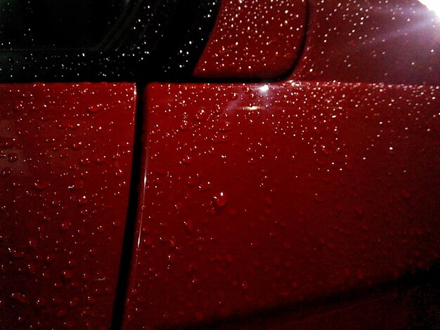 Fotografía detallada de gotas de agua en la superficie roja