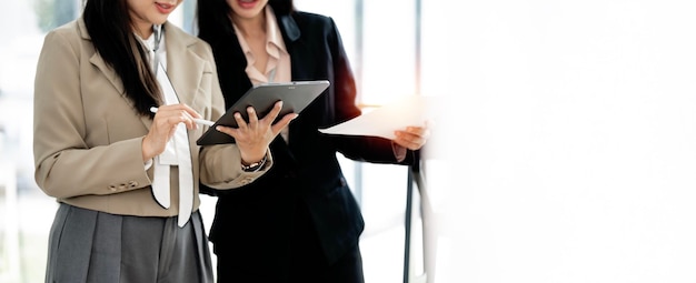 Fotografía de dos mujeres de negocios trabajando juntas en una tableta digital. Ejecutivas creativas se reúnen en una oficina usando una tableta.