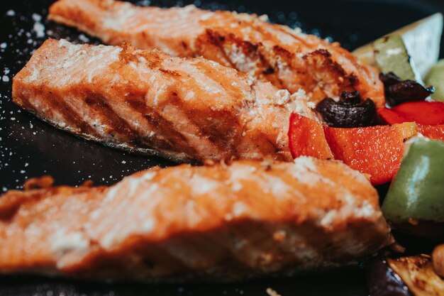 Fotografia em close de salmão grelhado com legumes fritos