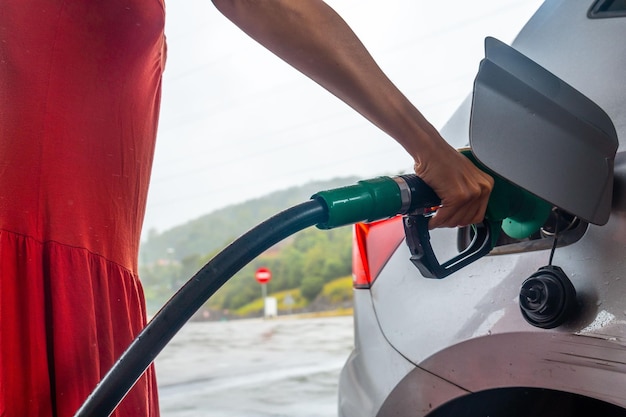 Foto fotografia em close de uma mulher reabastecendo seu carro com gasolina em um posto de gasolina