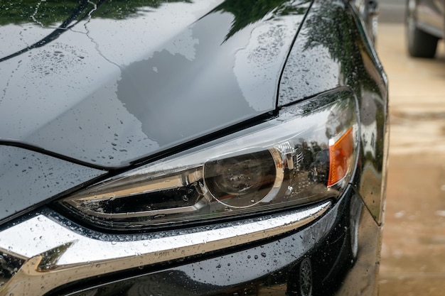 Fotografia em close-up de um carro preto coberto de água em uma lavagem de carros