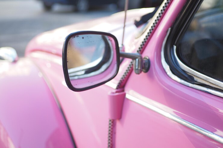 Foto fotografia em close-up de um espelho lateral de carros cor-de-rosa em um veículo clássico sob o sol