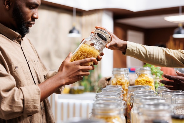 Foto fotografia em close-up de um homem afro-americano checando a pasta em frascos de vidro em um supermercado ecologicamente consciente um cliente masculino olhando para produtos nutritivos a granel