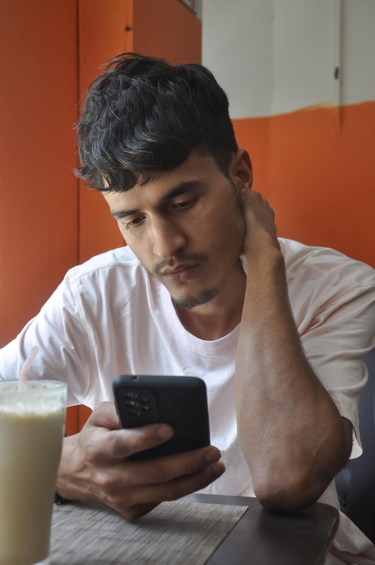 Foto fotografia em close-up de um jovem usando seu telefone enquanto estava sentado em um café
