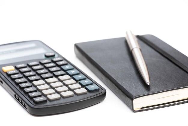 Foto fotografia em close-up de uma calculadora, um caderno e uma caneta isolados em um fundo branco