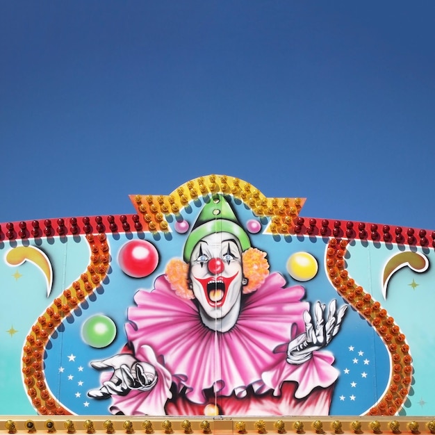 Fotografia em close-up de uma pintura de palhaço de circo na parede sob um céu azul