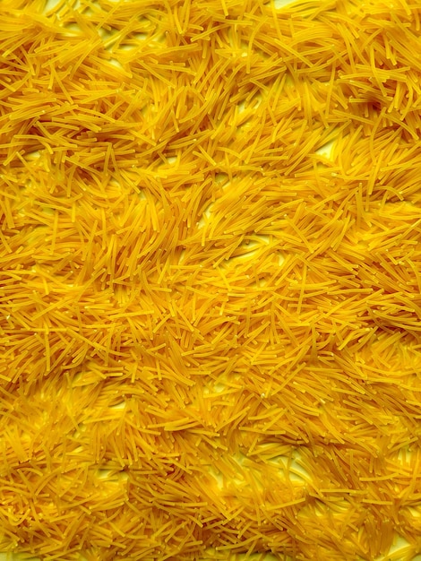 Fotografia em close-up de vermicelli amarelo mostrando sua forma fina e textura delicada