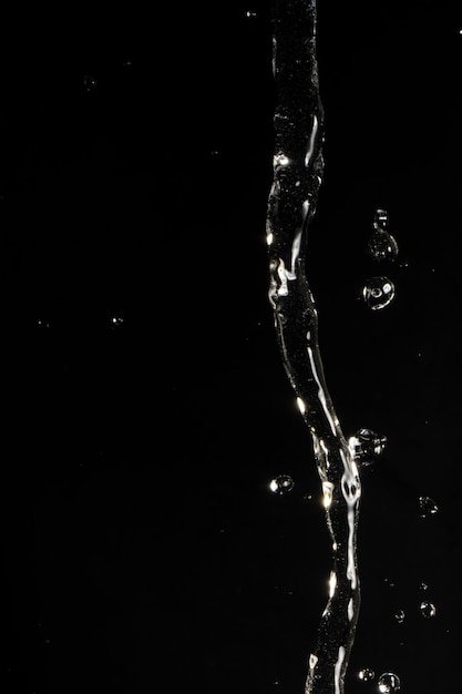 Foto fotografía de estudio de verter agua con reflejo de luz contra un fondo negro.