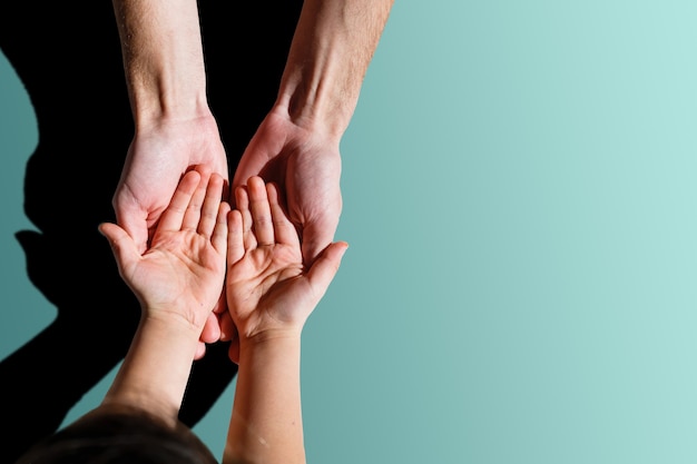 Una fotografía de familia en primer plano de un padre o un padre sosteniendo la pequeña mano abierta y los dedos de su bebé o hijo en la palma de su mano.