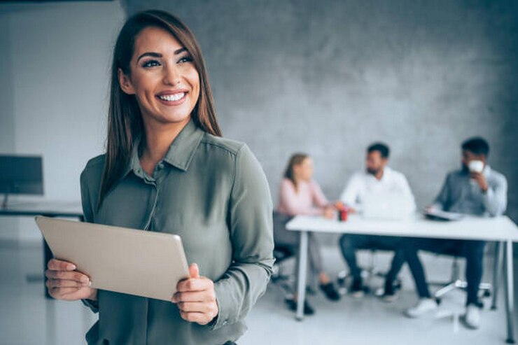 Fotografía de una hermosa mujer de negocios sonriente de pie frente a su equipo