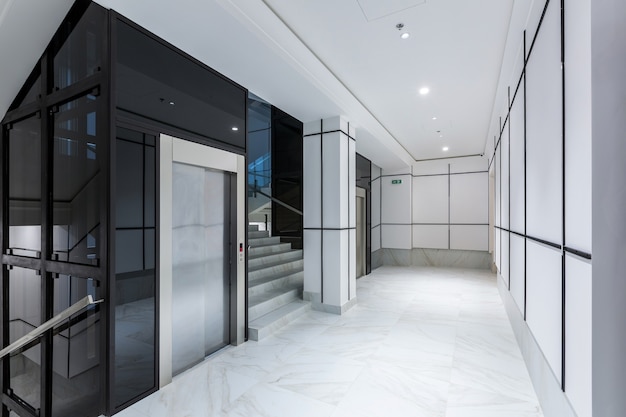Fotografía de interiores pasillo contemporáneo centro de negocios de pasillo en azulejos blancos con mármol